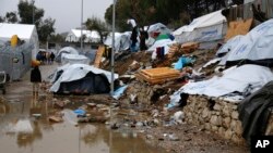 FILE - A refugee stands next to a pool of mud at Moria refugee camp on the eastern Greek island of Lesbos, Jan. 10, 2017. 