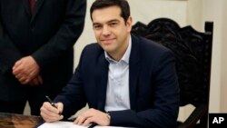 26일 그리스 대통령궁에서 새 총리로 취임한 급진좌파연합의 알렉시스 치프라스 총리가 취임 선서에 서명하고 있다.
