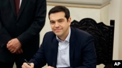 FILE - Greece's Prime Minister Alexis Tsipras poses for the photographers after taking a secular oath at the Presidential Palace in Athens, Jan. 26, 2015.