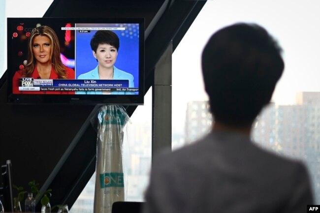 中国官方的英文电视频道中国环球电视网(CGTN)主播刘欣2019年5月30日在北京的中央电视台总部观看电视屏幕上播放的她接受美国福克斯商业频道主持人翠西·里根访谈的画面。
