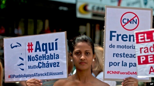 Partidarios del presidente venezolano, Nicolás Maduro, sostienen señales a favor de sus medidas durante una protesta frente a las oficinas del regulador de telecomunicaciones de Venezuela en Caracas.