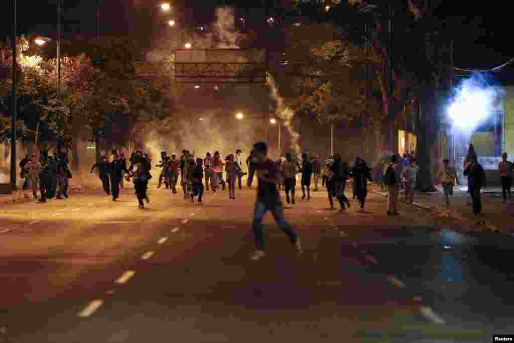 Anti-government demonstrators run from tear gas during clashes with riot police at Altamira Square in Caracas, Feb. 24, 2014.
