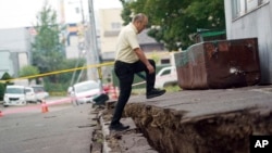 Seorang pria berjalan melewati jalanan yang tergeser setelah gempa di Kiyota, di pinggiran Sapporo, Hokkaido, utara Jepang, 7 September 2018. 
