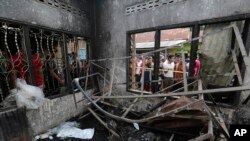 Warga mellihat kerusakan setelah kebakaran melalap pabrik korek api di Langkat, Sumatra Utara, 21 Juni 2019. (Foto: AP)