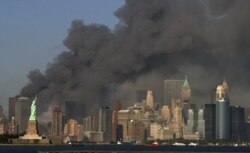 FILE -- In this Sept. 11, 2001 file photo, thick smoke billows into the sky from the area behind the Statue of Liberty, lower left, where the World Trade Center towers stood.