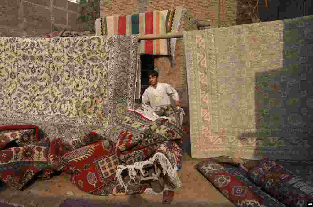 A boy transport dry carpets on a push-cart after washing them at a workshop in Peshawar, Pakistan.