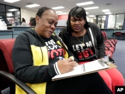 Former felon Yolanda Wilcox, left, fills out a voter registration form as her best friend Gale Buswell looks on at the Supervisor of Elections office, Jan. 8, 2019, in Orlando.