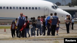 Guatemalan families, deported from Phoenix, Arizona in the U.S., walk at an air force base after arriving on a flight transporting illegal Guatemalan migrants, in Guatemala City, July 22, 2014. 