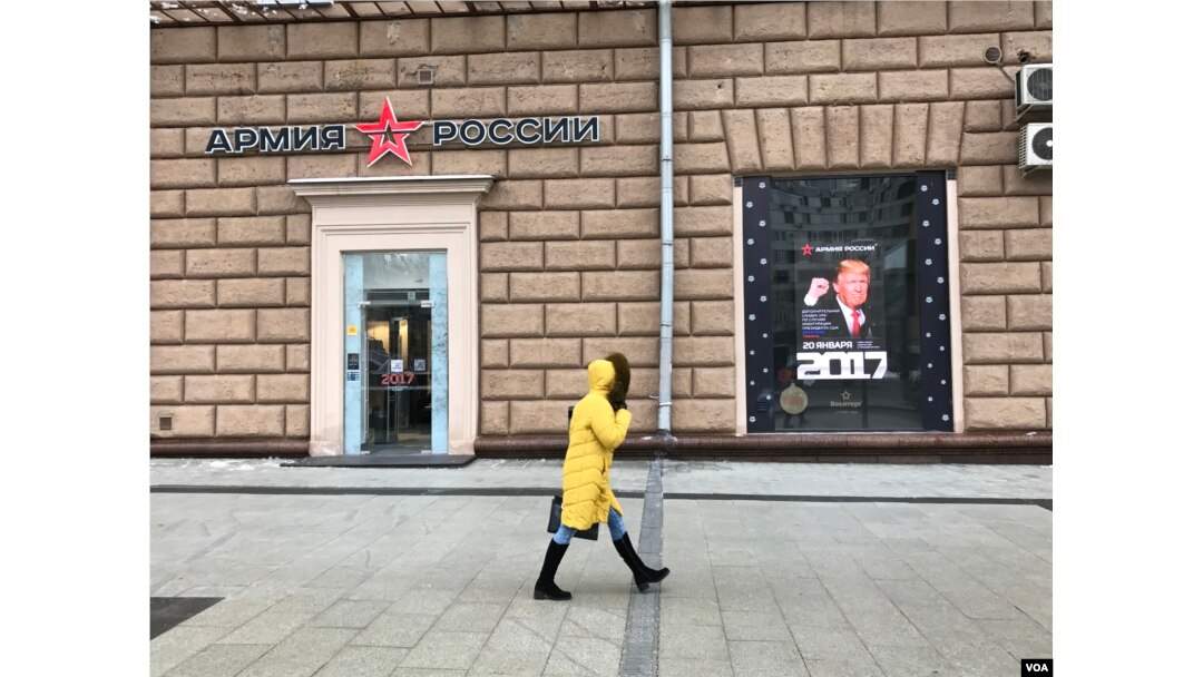 A woman walks by a Russian Army store displaying a poster of Donald Trump across from the U.S. embassy in Moscow, Jan. 20, 2016. (D. Schearf/VOA)