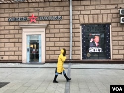 A woman walks by a Russian Army store displaying a poster of Donald Trump across from the U.S. embassy in Moscow, Jan. 20, 2016. (D. Schearf/VOA)