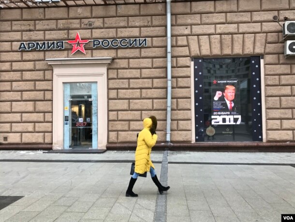 A woman walks by a Russian Army store displaying a poster of Donald Trump across from the U.S. embassy in Moscow, Jan. 20, 2016. (D. Schearf/VOA)