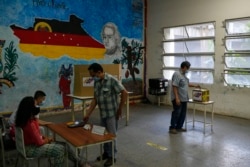 Seorang pemilih memberikan suaranya di tempat pemungutan suara selama pemilihan utama partai berkuasa Partai Sosialis Bersatu Venezuela di Caracas, Venezuela, Minggu, 8 Agustus 2021. (Foto: AP/Matias Delacroix)