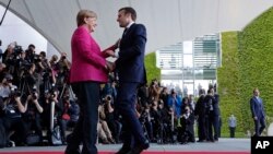New French President Emmanuel Macron is welcomed by German Chancellor Angela Merkel in Berlin, May 15, 2017, during his first foreign trip after his inauguration the day before.