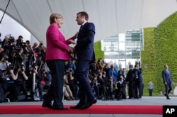 New French President Emmanuel Macron is welcomed by German Chancellor Angela Merkel in Berlin, May 15, 2017, during his first foreign trip after his inauguration the day before.