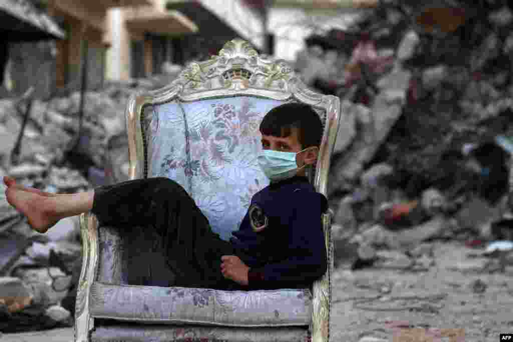 A child sits on a couch found in a street, ravaged by pro-government forces airstrikes, in the town of Ariha in the southern countryside of the Idlib province, Syria.
