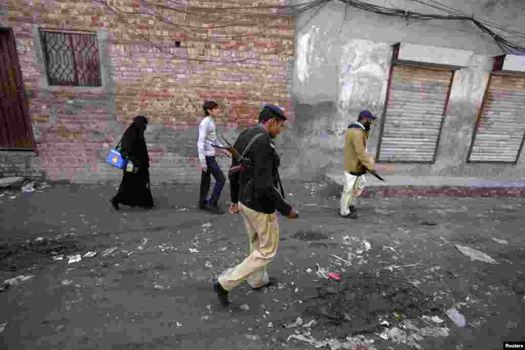 A policeman accompanies polio workers during their anti-polio drive mission in Lahore, Pakistan, December 20, 2012. 