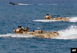 FILE - U.S. Navy amphibious assault vehicles with Philippine and U.S. troops on board are seen during joint exercises near a beach facing one of the contested islands in the South China Sea known as the Scarborough Shoal in the West Philippine Sea, April 21, 2015.