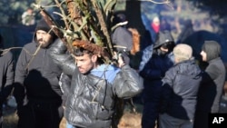 Un migrante lleva leña mientras otros migrantes de Oriente Medio y otros lugares se reúnen en la frontera entre Bielorrusia y Polonia cerca de Grodno, Bielorrusia, el 9 de noviembre de 2021.