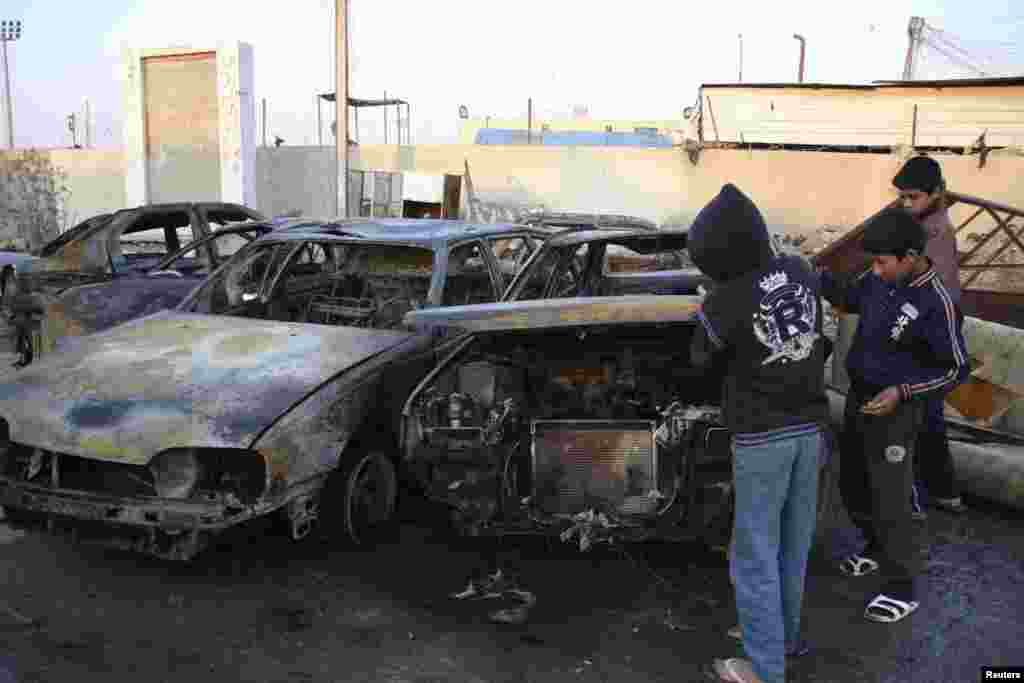 Young Iraqis survey damage at the site of a bomb attack, Ur district of northeastern Baghdad, Feb. 18, 2014. 