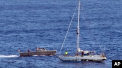 In this Oct. 25, 2017 photo, sailors from the USS Ashland approach a sailboat with two Honolulu women and their dogs aboard as they are rescued after being lost at sea for several months while trying to sail from Hawaii to Tahiti. 