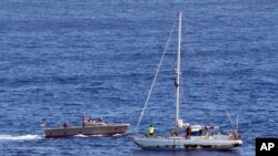 In this Oct. 25, 2017 photo, sailors from the USS Ashland approach a sailboat with two Honolulu women and their dogs aboard as they are rescued after being lost at sea for several months while trying to sail from Hawaii to Tahiti.