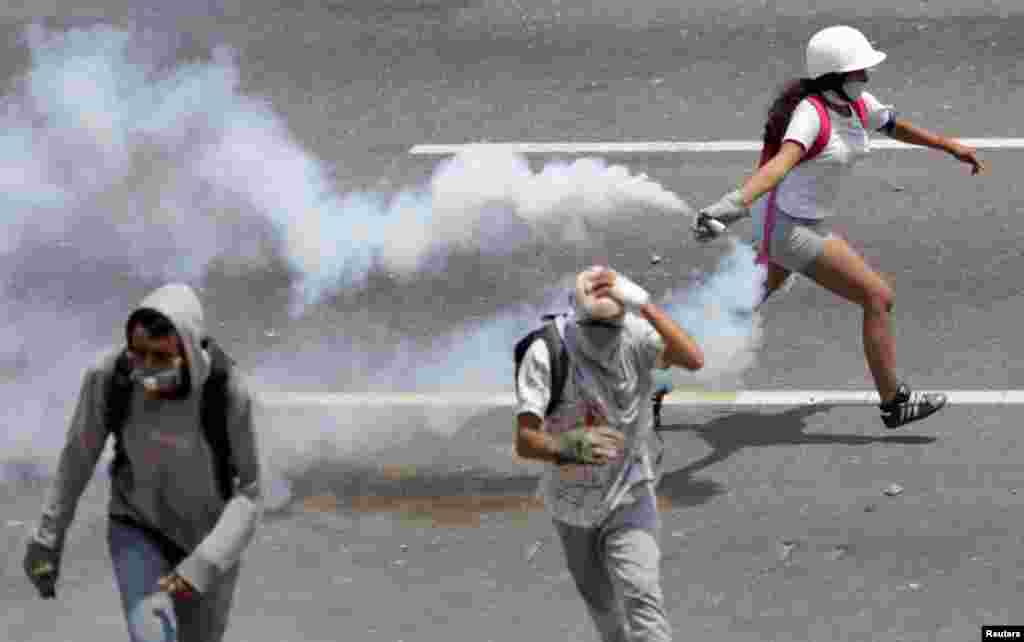 An opposition supporter runs with a tear gas canister during a rally against the government of Venezuela's President Nicolas Maduro and to commemorate May Day in Caracas, May 1, 2019.