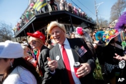 John Shreves, center, of New Orleans, runs into Jeff Jones, right, who both dressed as Donald Trump, during the Society de Sainte Anne parade, on Mardi Gras day in New Orleans, Tuesday, Feb. 13, 2018.