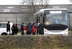 Migrants who were found soaked after a failed attempt to cross the Channel walk out from a shelter and take a bus to a warm place, in the rue des huttes in Calais, France, Nov. 25, 2021.