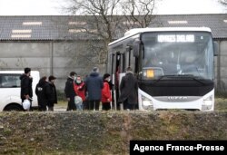 Migrants who were found soaked after a failed attempt to cross the Channel walk out from a shelter and take a bus to a warm place, in the rue des huttes in Calais, France, Nov. 25, 2021.