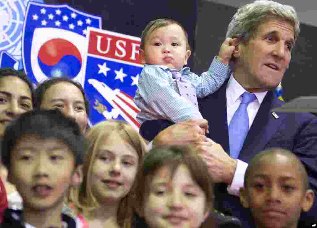 O Secretário do Estado, John Kerry, (Dir) carrega um bebé de oito meses, Andrew Belz, ao posar com os filhos das tropas Americanas e de funcionários da Embaixada EUA no Collier Field House no Yongsan Garrison em Seoul, Coreia do Sul.