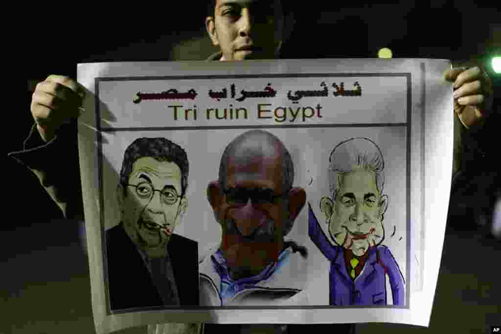 An Islamist protester supporting Egyptian President Mohammed Morsi holds a banner with picture of Egyptian opposition leaders Hamdeen Sabahi, right, leading democracy advocate Mohamed ElBaradei, center, former foreign minister and presidential candidate Amr Moussa during a protest in front of the Media City complex in Giza, Egypt, Wednesday, Dec. 12.