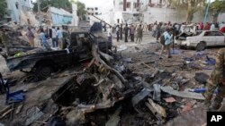 Rescue workers stand near the wreckage of vehicles in Mogadishu, Somalia, Oct. 29, 2017, after a car bomb was detonated Saturday night. A Somali police officer said security forces ended a nightlong siege at a Mogadishu hotel by attackers who stormed the building after a suicide car bomber detonated an explosives-laden vehicle at the gate.