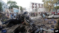 Anggota tim SAR, Minggu, 29 Oktober 2017, berdiri di dekat kendaraan yang hangus akibat ledakan akibat ledakan bom di Mogadishu, Somalia, Sabtu malam. Pasukan keamanan Somalia mengakhiri pengepungan di sebuah hotel di Mogadishu, setelah seorang pembom mobil bunuh diri meledakkan sebuah kendaraan yang dilengkapi dengan bahan peledak di pintu masuk hotel tersebut, Minggu (29/10).