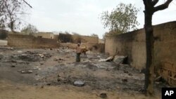 In this image shot with a mobile phone, a young girl stands amid the burned ruins of Baga, Nigeria, April 21, 2013.