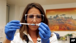 FILE - Felicity Hartnell, who is a clinical research fellow at Oxford University, holds a vial of an experimental vaccine against Ebola in Oxford, England, Sept. 17, 2014.