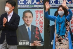 A supporter of Japan's governing Liberal Democratic Party waves by posters of Japanese Prime Minister Fumio Kishida during a campaign rally for the Oct. 31 lower house elections, in Tokyo, Oct. 27, 2021.