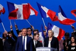 French conservative candidate from the first-round election Nicolas Dupont-Aignan, left, and french far-right presidential candidate Marine Le Pen sing the "Marseillaise", the French national anthem at the end of their meeting, May 1, 2017, in Villepinte.