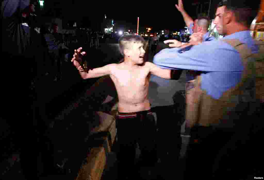 Iraqi security forces detain a boy after removing a suicide vest from him in Kirkuk, Iraq, Aug. 21, 2016.