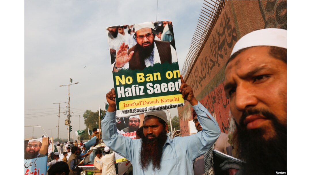 FILE - A supporter of Islamic charity organization Jamaat-ud-Dawa (JuD) carries a sign during a protest demonstration in Karachi.