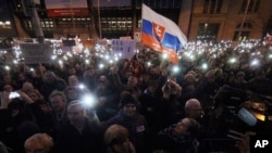 In this March 9, 2018 photo, demonstrators hold up their smartphones during an anti-government rally in Bratislava, Slovakia.