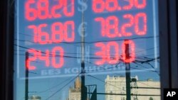 FILE - The building of the Russian Foreign Ministry, center rear, is reflected in a sign showing currency exchange rates in Moscow, Russia.