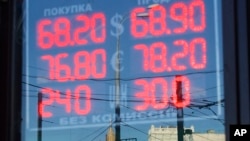 FILE - The building of the Russian Foreign Ministry, center back, is reflected in a sign showing currency exchange rates in Moscow, Russia, Aug. 21, 2015. 