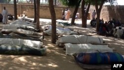 FILE - People are seen next to dead bodies, laid out for burial, in the village of Konduga, in northeastern Nigeria, on Feb. 12, 2014, after an attack by Boko Haram militants killed 39 people.