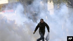 A protester runs from tear gas during clashes with security forces near the Interior Ministry in Cairo, February 5, 2012.