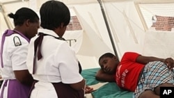 FILE: A woman is attended to after suffering from a suspected case of typhoid at a local hospital in Harare, January 31, 2012.