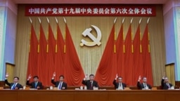 在新华社发布的这张照片中，包括中国国家主席习近平（中）和国务院总理李克强（右三）在内的中共中央政治局常委在十九大会议上举手。
