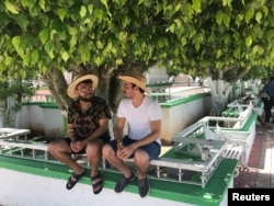 Graphic designer Carlos Alfredo Ramos (L) and artist Isaac Cabrera Leon chat while sitting in the shade of a park in Tepetitan, Mexico, July 1, 2018.