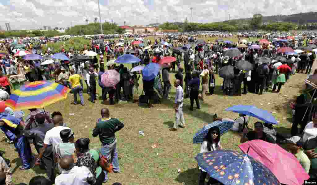People line up for courtesy buses to ferry them to the Union Buildings to view the body of Nelson Mandela in Pretoria, Dec. 12, 2013.