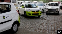 Ola cabs, left, waiting for customers, are parked next to other cars in Kolkata, India, March 29, 2016.