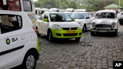 Ola cabs, left, waiting for customers, are parked next to other cars in Kolkata, India, March 29, 2016.